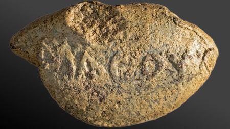 A close up of a yellow and gray stone with lettering carved into its round face