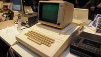 A close up of a large white computer with a boxy monitor and keyboard. 